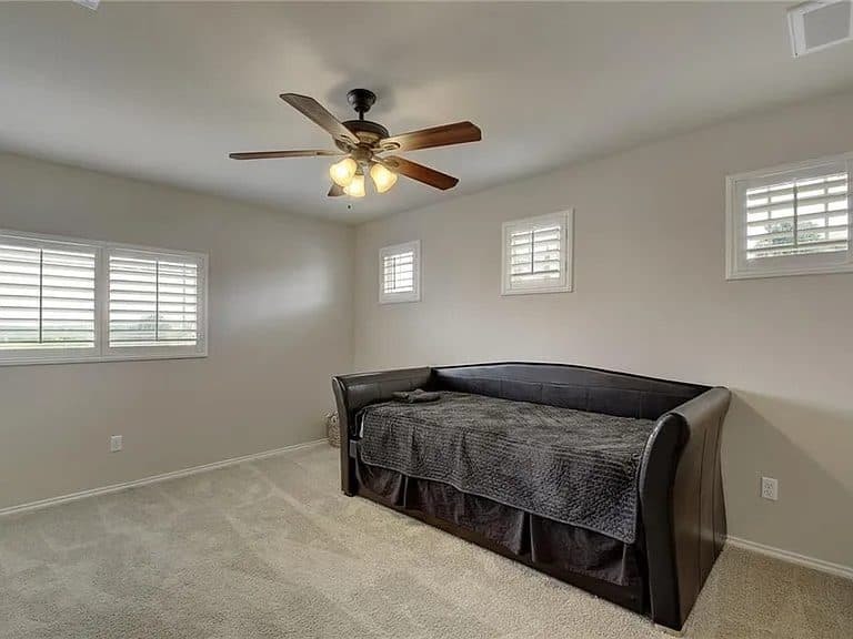 A plain, light-filled kids room before its redesign — bare walls, a single window, a generic bed, and a few scattered toys.